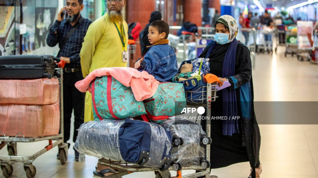 A Bangladeshi national (R) carries luggage on a trolley upon her arrival from Lebanon, at the Hazrat Shahjalal International Airport in Dhaka on October 21, 2024. - The first Bangladeshis airlifted home after fleeing Israeli airstrikes in Lebanon described the constant fear of living in a city rocked by explosions. Late on October 21, the first 54 of some 1,800 Bangladeshis wanting to escape the troubled Mediterranean nation flew back to Dhaka on a government-backed flight. (Photo by Salahuddin Ahmed / AFP)