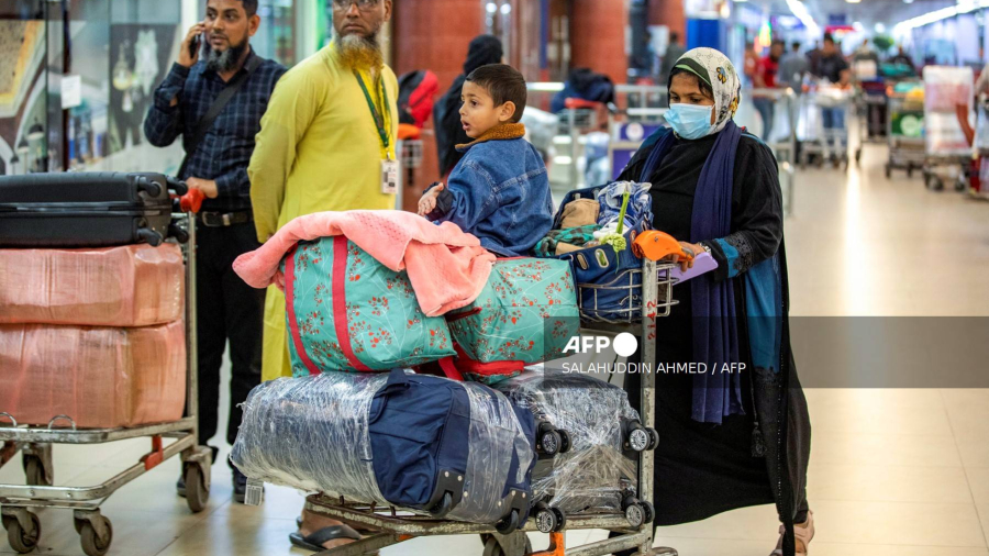 A Bangladeshi national (R) carries luggage on a trolley upon her arrival from Lebanon, at the Hazrat Shahjalal International Airport in Dhaka on October 21, 2024. - The first Bangladeshis airlifted home after fleeing Israeli airstrikes in Lebanon described the constant fear of living in a city rocked by explosions. Late on October 21, the first 54 of some 1,800 Bangladeshis wanting to escape the troubled Mediterranean nation flew back to Dhaka on a government-backed flight. (Photo by Salahuddin Ahmed / AFP)